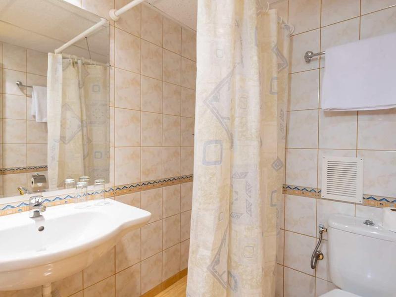 Small bathroom with shower, sink, toilet, and light-colored tiles.