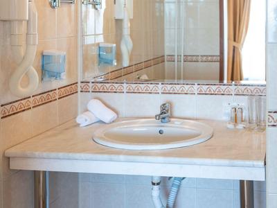 Heller Hotelbadezimmerwaschtisch mit großem Spiegel und zwei runden Vergrößerungsspiegeln an der Wand.