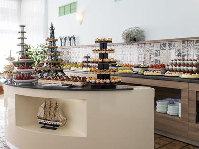 Buffet mit verschiedenen Süßigkeiten auf mehrstufigen Servierregalen in einem hellen Raum.
