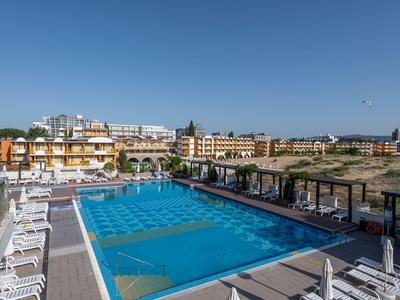 Großer Außenpool eines Hotels mit Liegestühlen und Blick auf umliegende Gebäude bei klarem Himmel.