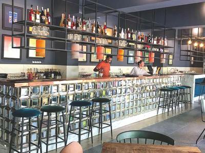 Moderne hotelbar met veel barkrukken en flessenrekken aan de muur.