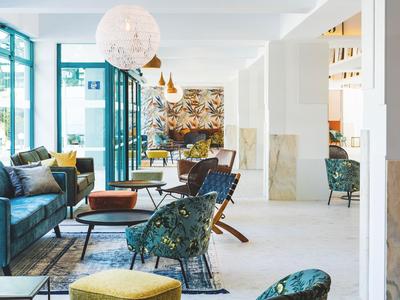 Lichte, moderne hotel-lounge met kleurrijke patroonstoelen, banken en grote ramen.