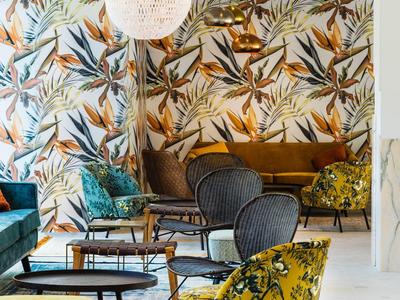 Moderne woonkamer met kleurrijk vogelpatroon aan de muur en gezellige fauteuils.