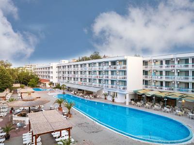 Großer Außenpool vor einem weißen Hotel mit mehreren Stockwerken, umgeben von Sonnenschirmen und Sitzbereichen.