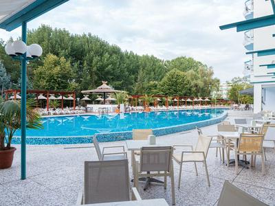 Recreatiegebied met groot zwembad, parasols en terrasstoelen bij een hotelresort.