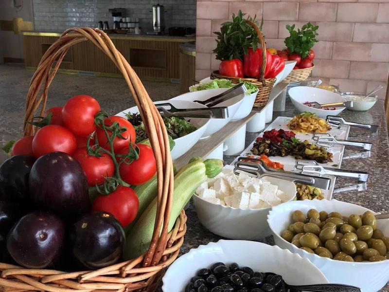 Korb mit frischem Gemüse und Teller mit Oliven und weiteren Speisen auf Küchenzeile.