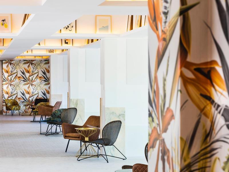 Moderner Wartebereich mit gemusterten Wänden, Sesseln und hellem, offenem Raum.