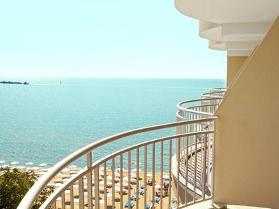 Balkon met metalen railing met uitzicht op zee en strand met parasols.