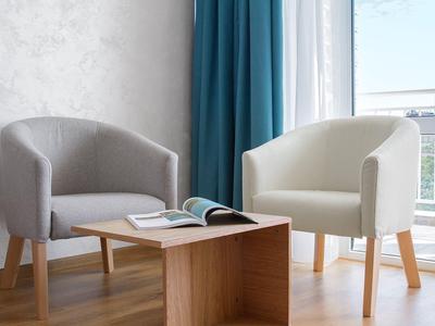 Twee moderne fauteuils en een kleine houten tafel bij een raam in een lichte kamer.