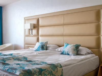 Hotelkamer met een groot bed, gevoerd hoofdeinde en lichtblauwe accenten.