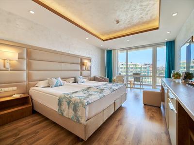 Modern hotelkamer met tweepersoonsbed, houten vloer en balkon met zeezicht.