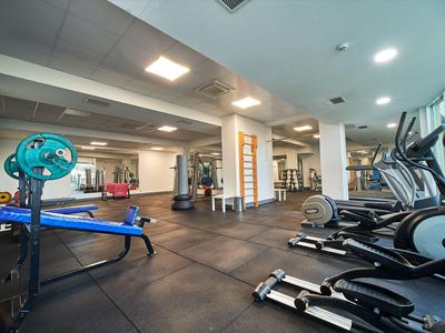 Gimnasio moderno con máquinas de ejercicio y pesas en un espacio interior luminoso.