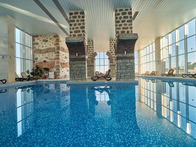 Binnenzwembad met grote ramen en stenen muren in een modern hotel.