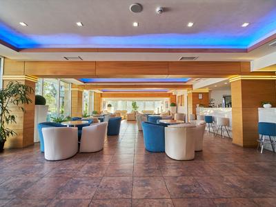 Zona lounge moderna de hotel con sillones y bar en un ambiente cálido y acogedor.