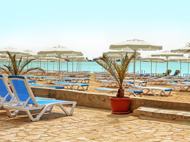 Lege blauwe ligstoelen en parasols naast een zwembad aan zee op een zonnige dag