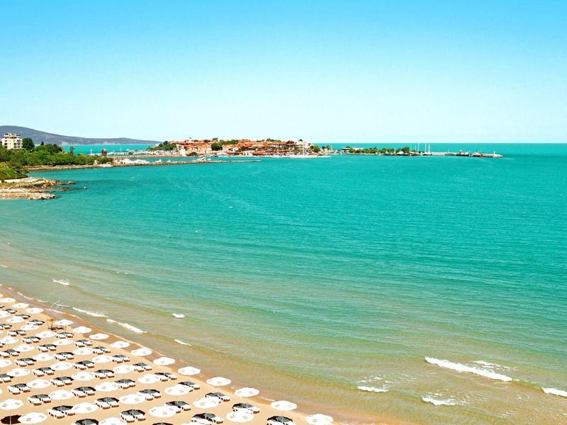 Strand met rijen zonneparasols en blauwe zee die tot de horizon reikt.