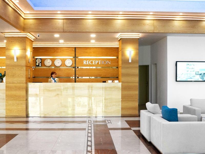 Lichte hotellobby met receptiebalie en moderne banken in neutrale kleuren.