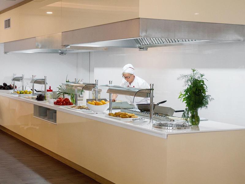 Buffet met diverse gerechten en een chef-kok in een moderne keuken.