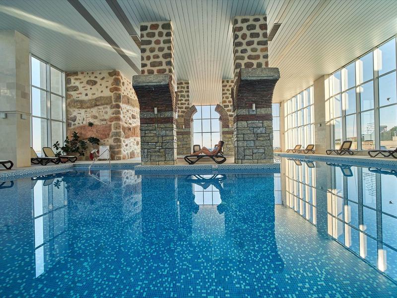 Binnenzwembad met grote ramen en stenen muren in een modern hotel.