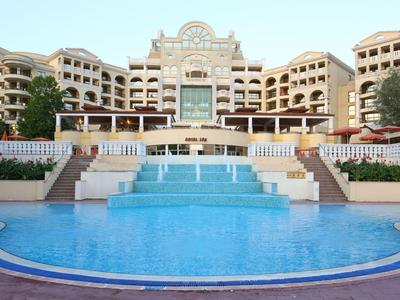 Duży budynek hotelowy z wieloma piętrami i dużym basenem na pierwszym planie.