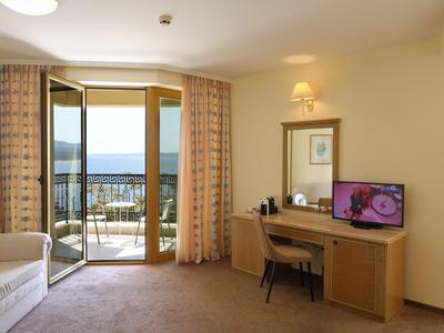 Camera d'hotel con balcone, tavolo, sedia, divano e TV con vista sul mare