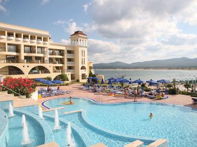 Hotel con ampie piscine all'aperto, ombrelloni e vista mare sotto un cielo limpido