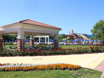 Park rozrywki z pawilonem, kolorowymi klombami i zjeżdżalniami wodnymi pod czystym niebem