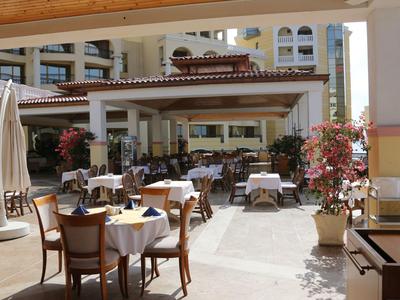 Area pranzo all'aperto con tavoli apparecchiati e sedie accanto a un edificio alberghiero.