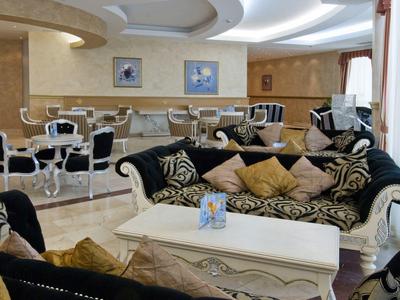 Elegante lounge dell'hotel con poltrone di stile, divani e tavolo bianco in ambiente luminoso.