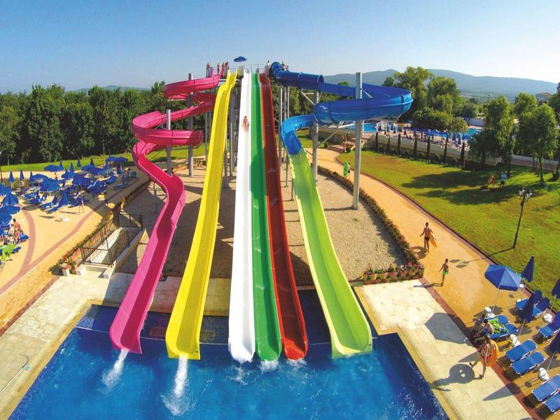Scivoli d'acqua colorati in un parco acquatico con piscina e lettini all'aperto.