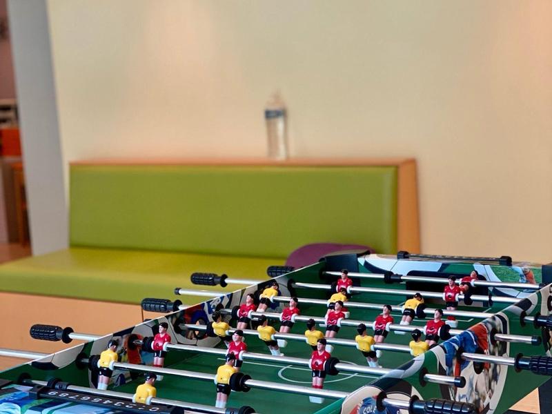 Calcio balilla con design colorato in una stanza moderna con una panchina verde.