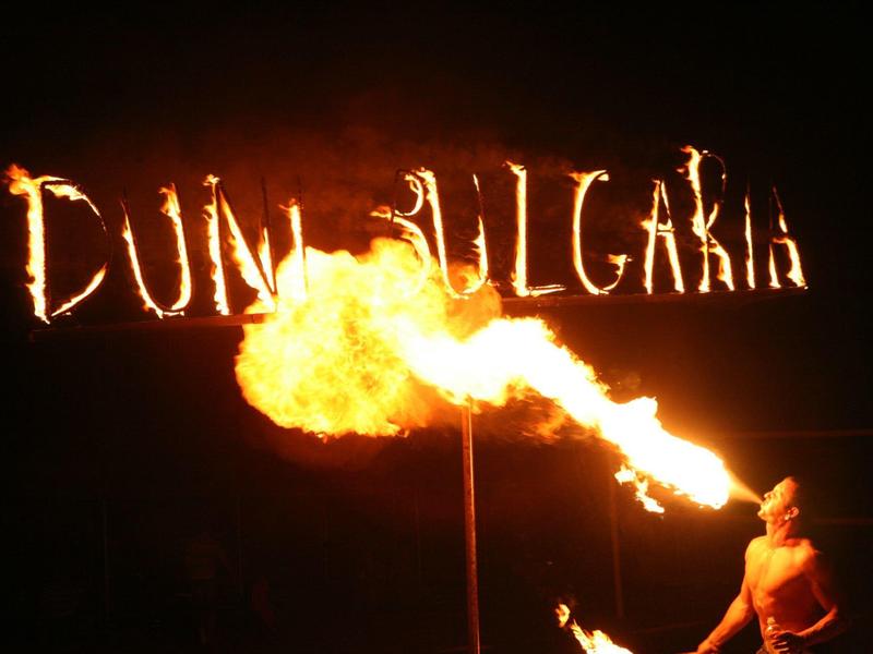 Sputafuoco di notte davanti al cartello Duni Bulgaria con fiamme.