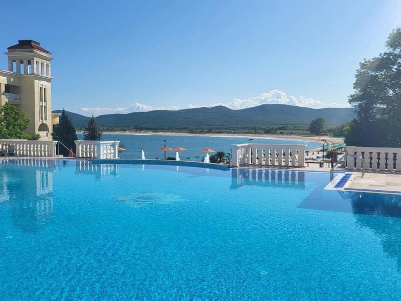 Piscina a sfioro con vista su lago e montagne sotto cielo limpido.