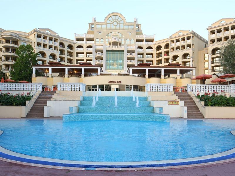 Hotel di lusso con grande piscina e cascata su più livelli sotto il cielo azzurro.