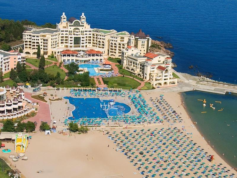 Hotel di lusso con grandi piscine, ombrelloni e spiaggia privata sul mare.