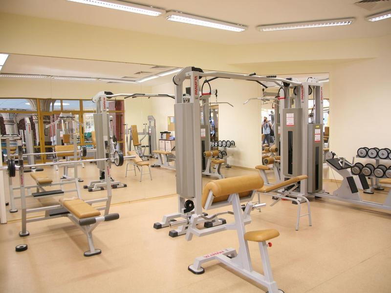 Palestra luminosa con attrezzature moderne e parete a specchio per allenamento di forza.