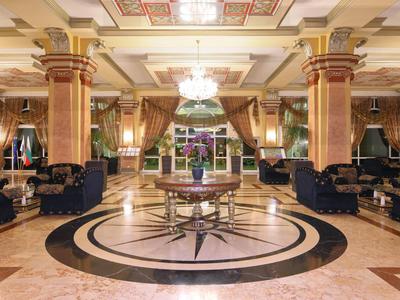 Ruime hotel lobby met marmeren vloer, zuilen en elegante zitgedeelten in de avond.