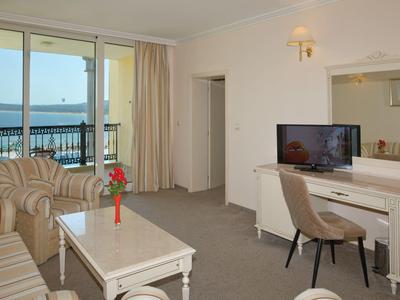 Gezellige woonkamer met bank, tv, tafel en zeezicht vanaf een balkon.