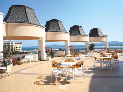 Terras met tafels en stoelen met uitzicht op zee en lucht bij helder weer.