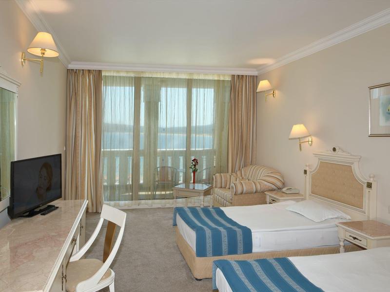 Hotelkamer met twee eenpersoonsbedden, bureau, tv en balkon met uitzicht.