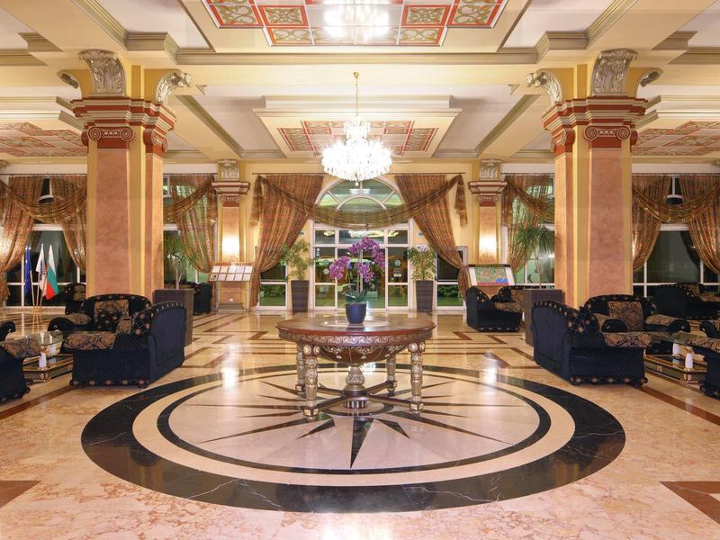 Ruime hotel lobby met marmeren vloer, zuilen en elegante zitgedeelten in de avond.