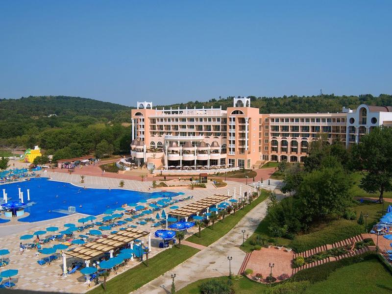 Groot meerkamerhotel naast een zwembad met ligbedden en parasols.