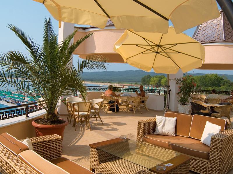 Terras met zithoek, parasols en uitzicht op water en bergen.