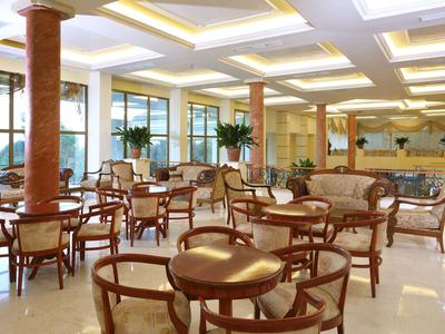 Lichte en elegante hotel eetruimte met houten tafels en stoelen, grote ramen en planten.