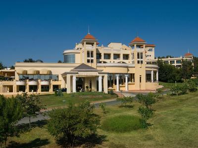 Groot elegant hotelgebouw onder een heldere blauwe lucht met verzorgde tuin