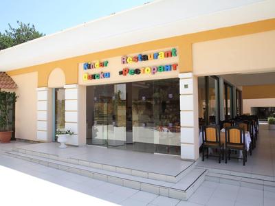 Exterieur van een licht gebouw met een kleurrijk bord en zithoek rechts.