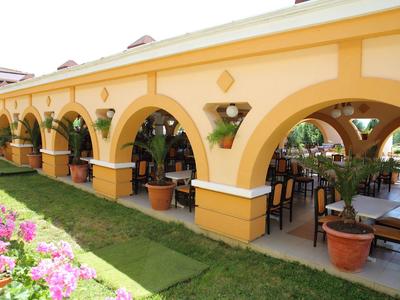 Žlutá arkáda s posezením a kvetoucí zahradou v hotelovém areálu.
