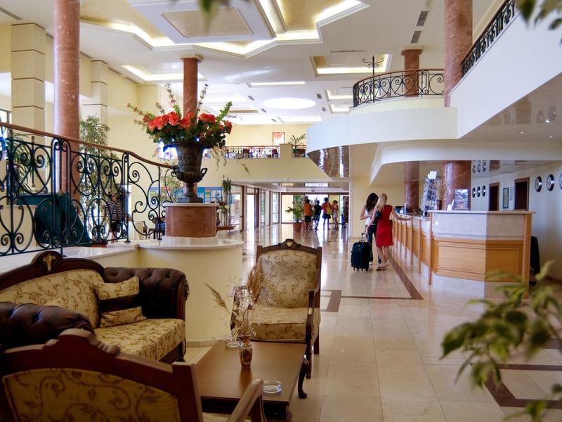 Lichte hotellobby met elegante zitmeubelen, receptiebalie en bloemendecoraties.