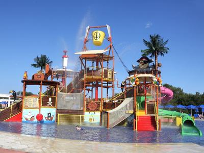 Parco acquatico colorato con scivoli e palme sotto un cielo limpido.