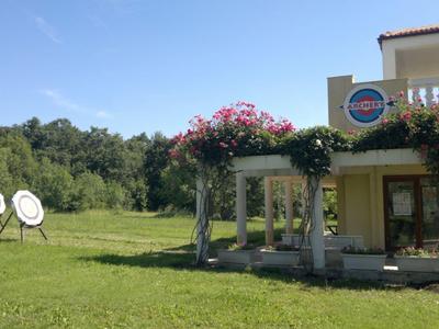 Grünes Feld mit Pfeilzielscheiben und Gebäude mit blühenden Pflanzen auf der Terrasse